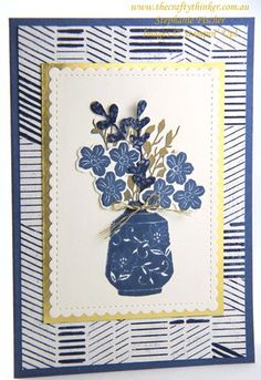 a card with blue flowers in a vase on the front and bottom, along with an embossed border