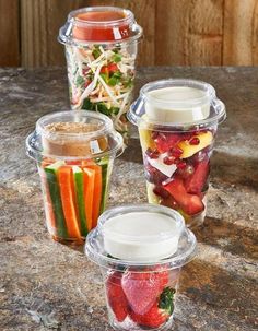 three plastic cups filled with different types of food on top of a table next to each other