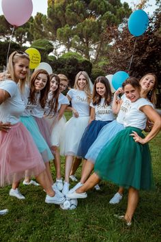 a group of young women standing next to each other on top of a lush green field