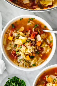 two bowls filled with vegetable soup on top of a table