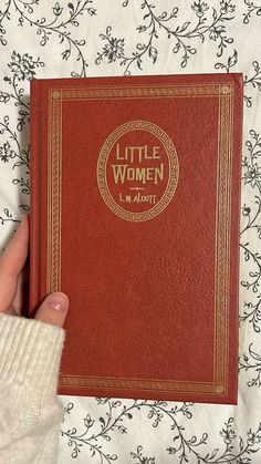 a person holding a little women book in their hand