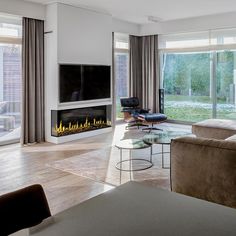 a living room with couches, chairs and a fire place in front of a large window