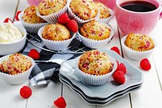 muffins on plates with raspberries next to them and a cup of coffee