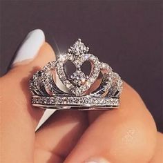 a woman's hand holding a ring with a tiara on top of it