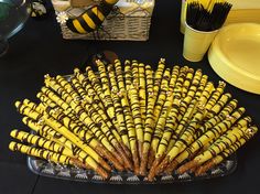 there are many yellow and black items on the table with plates, cups, and napkins