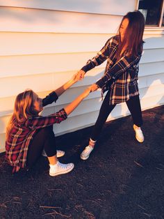 two girls holding hands while standing in front of a house