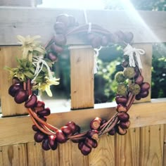 a close up of a wreath made out of grapes on a wooden fence with sunlight coming through the window