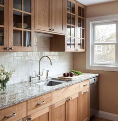 a kitchen with wooden cabinets and marble counter tops, along with a window over the sink