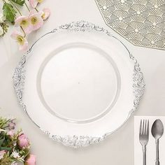 a white plate sitting on top of a table next to silverware and pink flowers