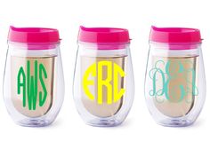 three personalized stemless wine glasses with monogrammed lettering on the bottom and pink lid