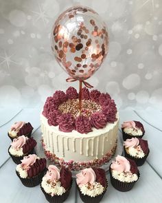 a cake with cupcakes and a balloon on top