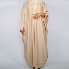 Drape yourself in our new line of luxurious open abayas. Their batwing design and open style allows the fabric to drape beautifully and create movement. The fabric is textured with a slight and subtle sheen when steamed. The solid colours and the classic cut make this abaya a classic staple that is a must have in your wardrobe. Perfect for those who don't want the distractions of a busy design. The wide sleeves with the small split gives it that contemporary touch. Included are a matching slip and hijab. Available in various colours, please check the store.   Available in Sizes: 50, 52, 54, 56, *58 and 60. Please choose your size from the drop down menu. *Please note 58 has slight machine defects and the price does reflect this.  Here at Pixie Plum we're proud to bring you a collection of Solid Long Thobe For Eid, Long Thobe For Eid, Floor-length Beige Abaya For Eid, Modest Long Solid Color Kaftan, Beige Long Thobe For Eid, Long Modest Abaya With Dabka, Modern Abaya Dubai, Open Abayas, Eid Abaya