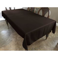 a dining room table with a brown cloth on it and two chairs in the background