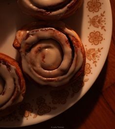 three cinnamon rolls on a plate with icing