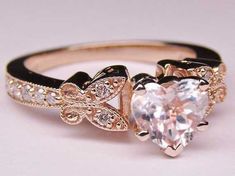 an engagement ring with a heart shaped diamond in the center and two smaller hearts on each side