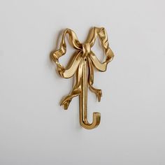 a gold metal object with a bow on it's back and the letter j