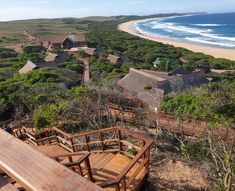 an aerial view of the ocean and beach from above, with wooden steps leading to houses