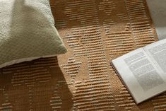 an open book sitting on top of a table next to a pillow and blanket covered floor