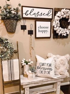 a white table topped with lots of pillows next to a wall filled with pictures and wreaths