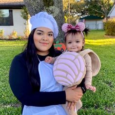 a woman holding a baby in her arms wearing a minnie mouse costume and mickey ears