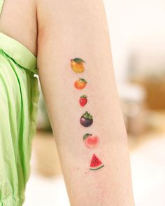 a woman's arm with fruit tattoos on the left side of her body, including watermelon, oranges, and strawberries