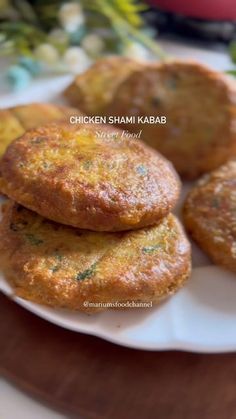 some fried food on a white plate with green leaves and flowers in the back ground