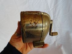 a hand holding an old metal object on a white background