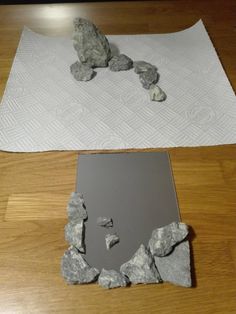 two pieces of rock sitting on top of a wooden floor next to a piece of paper