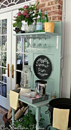 a shelf filled with lots of bottles and glasses on top of a wooden table next to a door