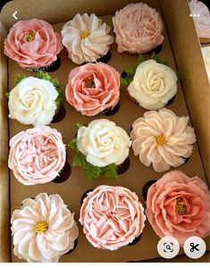 cupcakes decorated with pink and white flowers in a box