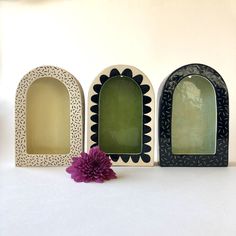 three different shaped frames sitting next to each other with a flower in front of them