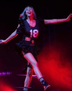 a woman in black dress on stage with her arms out and legs spread wide open