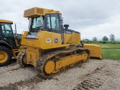 two large yellow machines are parked in the dirt