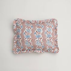 a pink and blue floral pillow on a white background