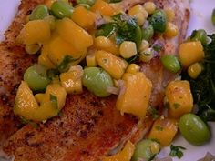 a white plate topped with fish covered in cheese and veggies next to green beans