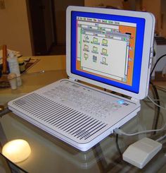 an open laptop computer sitting on top of a glass table next to a white mouse