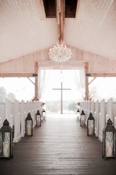 the aisle is lined with white chairs and lanterns