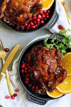 two black pans filled with food and garnished with orange slices, cranberries, and greens