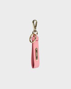 a pink keychain hanging from a metal hook on a white background with a gold chain