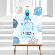 an easel with a sign that says blast off welcome to cayden's first birthday