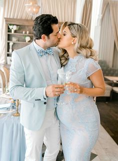 a man and woman kissing each other in front of a table with blue cloths