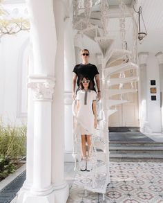 a man and woman standing on top of a white staircase