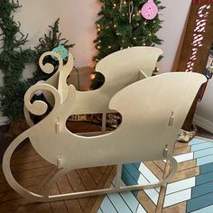 a wooden sleigh sitting on top of a floor next to a christmas tree