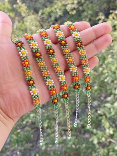 the hand is holding four bracelets with beads