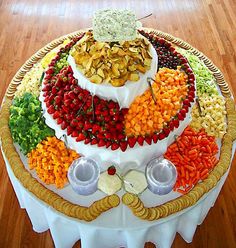 a platter filled with fruit and nuts on top of a white tablecloth covered in wood flooring