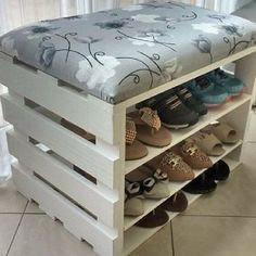 a bench made out of wooden pallets with shoes on the bottom shelf and an upholstered cushion