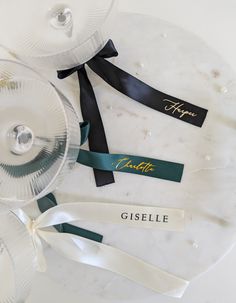 three wine glasses with name tags on them sitting on a white table top next to each other