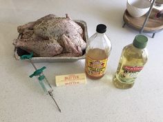 a chicken sitting on top of a counter next to bottles and a syringe