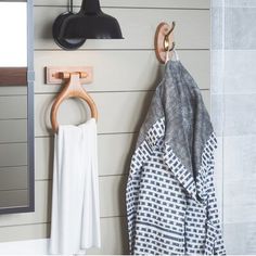 towels hanging on hooks in a bathroom next to a mirror and towel rack with an iron hook