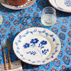 a blue and white plate with flowers on it next to silverware, utensils and glasses